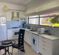 A kitchen in a 2-room apartment with white cabinets and a large window.