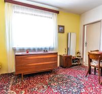 Living room in a two-room apartment with a patterned carpet and wooden furniture.