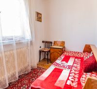 Simple bedroom with a bed, red carpet, chair, and wood-patterned floor.