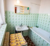 A bathroom with green tiles and a bathtub in a 2-room apartment.