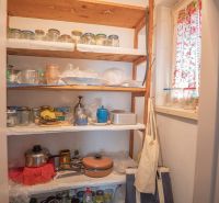A pantry in a 2-room apartment with wooden shelves and jars for canning.