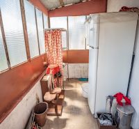 A balcony with a refrigerator, flower pots, and plastic windows in a 2-room apartment.