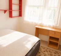 Interior of a 3-room apartment with a bed, a desk, and a red shelf.