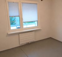 Empty room with a gray floor and a window in a 3-room apartment.