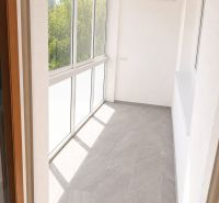 A glazed terrace in a 3-room apartment with tiles and a large window, brightening the space.
