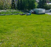 Grassy residential plots in Horná Ves with a garden house and trees in the background.