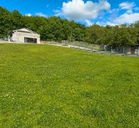 A green plot in Horná Ves for living, surrounded by houses and trees.