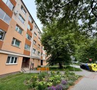 Exterior of a 2-room apartment on Palárikova Street in Senica, with nearby greenery and a park bench.