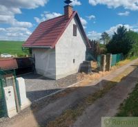 A cottage in Holíč with a slanted roof, an adjacent road, and open countryside.