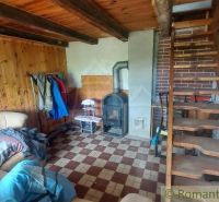 The interior of the cabin with wooden paneling, a stove, and a wooden staircase.