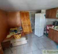 A kitchen in a cabin with wooden decor, appliances, and furniture in a rustic style.