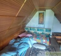 Interior of a cabin with wooden wall decor, a bed, and colorful blankets.