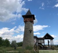 Stone lookout tower near the cottage in Holíč with a wooden roof and an information panel.