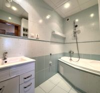 A bathroom in a 3-room apartment with a shower and a bathtub, tiled with light tiles.