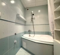 A bathroom with a bathtub and storage shelves in a 3-room apartment.