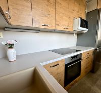 A kitchen in a 3-room apartment with a wood-patterned floor and modern appliances.