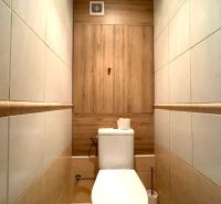 Bathroom in a 3-room apartment with tiles and a toilet, wooden decor on the wall.