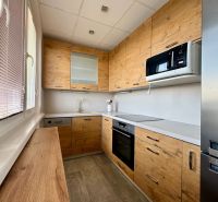A kitchen in a 3-room apartment with a wooden decor floor and modern equipment.