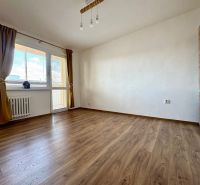 A room in a three-room apartment with a wood-decorated floor and a large window.