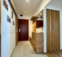 A hallway in a 3-room apartment with a tiled floor, a mirror, and wooden decor.