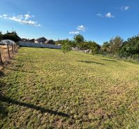 Gardens in Dvory nad Žitavou with a lawn, fence, and a cloudless sky.