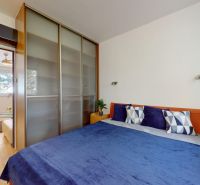 A bedroom in a 4-room apartment with a large bed, built-in wardrobe, and wooden decor flooring.