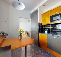 A kitchen in a 4-room apartment with wooden decor and flowers on the table.