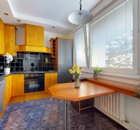 The kitchen of a 4-room apartment with wooden decor furniture and dark tiles.