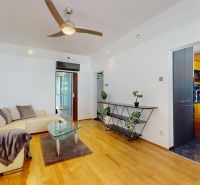 Living room in a 4-room apartment with a wooden decor floor, sofa, and kitchen.