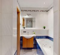 A bathroom with a bathtub and a sink in a 4-room apartment with white tiles.