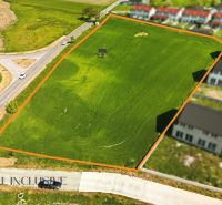 Plots - housing in Lehnice. Greenery separated by a road, surrounding construction of properties.