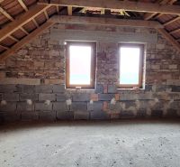 The attic of a family house with a brick wall and two windows.