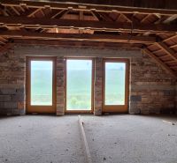 The attic of a family house with wooden beams and large glass doors.
