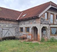 A family house in Stará Bašta made of gray brick with a red roof and wooden doors.