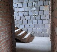 A view of an unfinished staircase in a family house with brick walls.