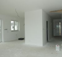 Interior of a family house with windows, preparation for floors, and white walls.