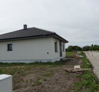 A family house in the town of Reca with a sloped roof, undeveloped surroundings, and a gravel road.