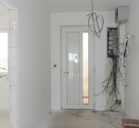 In the family house, there is unfinished electrical wiring with hanging cables and a fuse box.