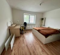 A room in a family house with a bed, a desk, and a wooden-decor floor.