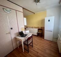 Interior of a 3-room apartment with wood-patterned flooring, a desk, and a refrigerator.