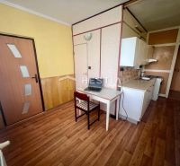 A kitchen in a 3-room apartment with a wooden decor floor and light furniture.