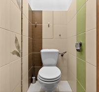 A toilet with tiles in a 3-room apartment, with ceramic tiles and toilet paper.