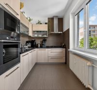 A kitchen with corner cabinets, built-in appliances, and a large window in a 3-room apartment.