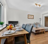 Dining room with a wooden table and a living room in a 3-room apartment with a wooden decor floor.