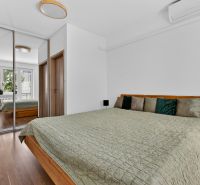 A bedroom in a 3-room apartment with a bed, a wardrobe, and a floor with a wooden decor.