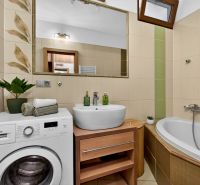 Bathroom with a washing machine, sink, and bathtub in a 3-room apartment. Walls with decorative tiles.