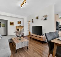 Living room in a three-room apartment with a wooden decor floor, beautiful furniture, and a dining area.