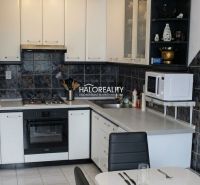 A kitchen unit with white cabinets and dark tiled backsplash in a 3-room apartment.