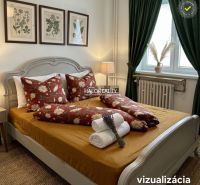 Bedroom with a floral motif on the bed in a 3-room apartment, green curtains, paintings on the wall.