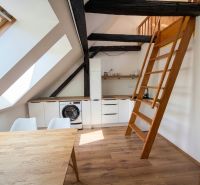 A kitchen in a 2-room apartment with skylights, a staircase, and a wooden decor floor.